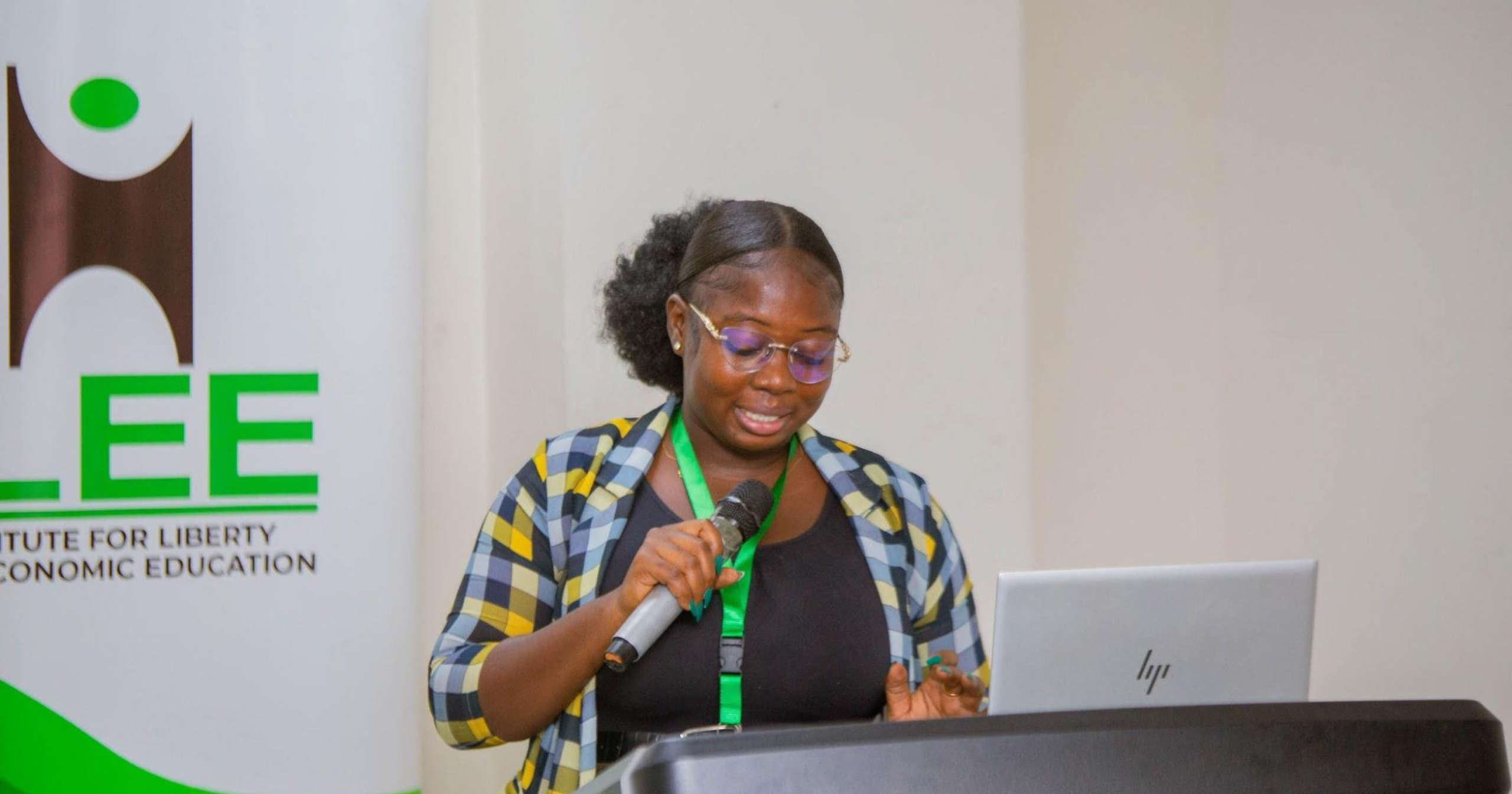 A presenter speaks at a podium during an Institute for Liberty and Economic Education (ILEE) event while delivering remarks to participants.