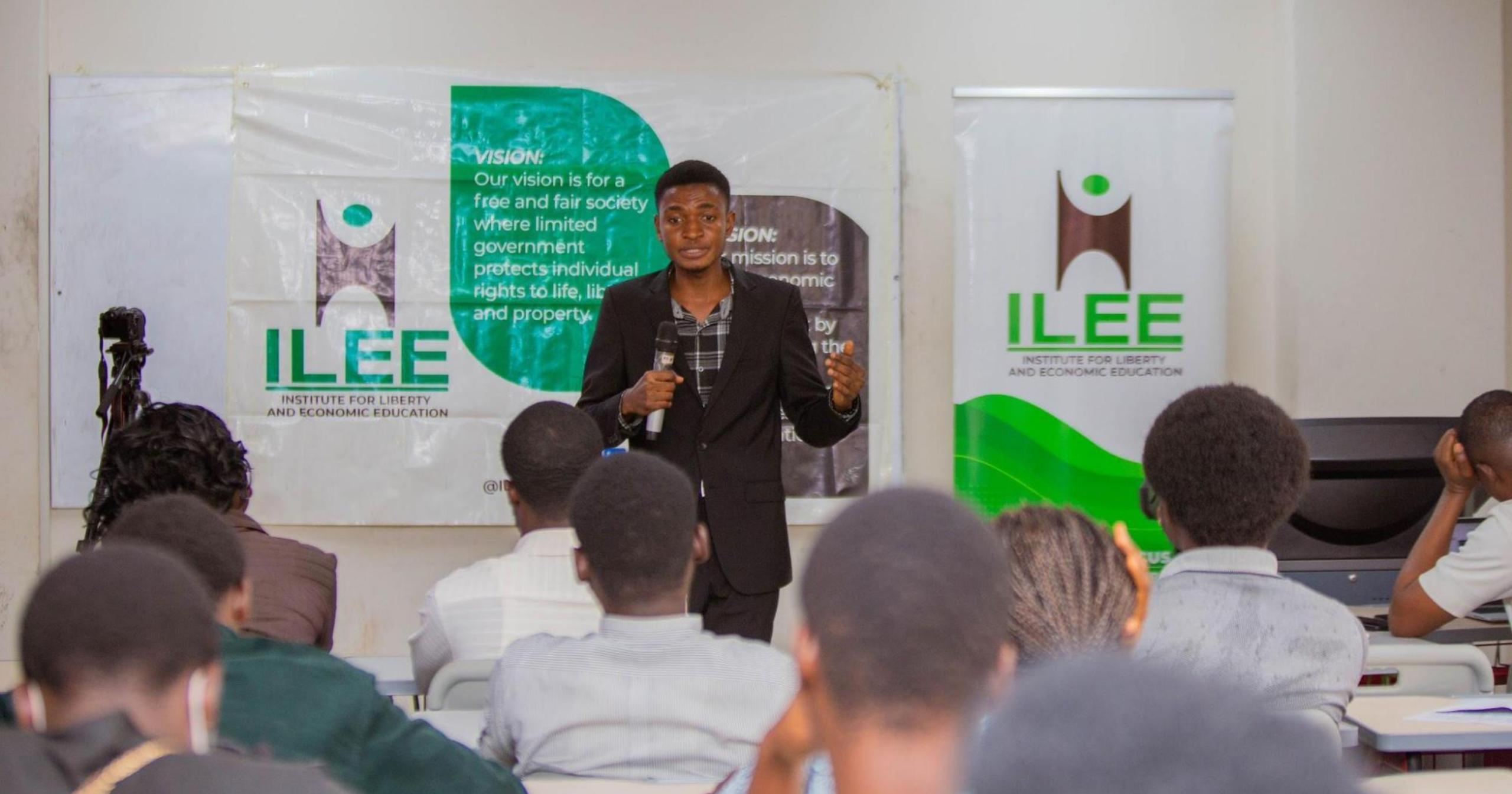 A speaker addresses participants during an Institute for Liberty and Economic Education (ILEE) educational event while presenting to an audience in a classroom setting.